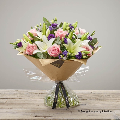 White Lily Purple Lisianthus Pink Rose & Greenery in a hand tied bouquet
