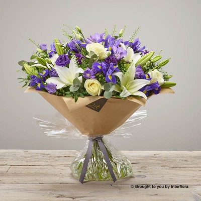 Purple Freesia Blue iris White Lily Purple Lisianthus Ivory Rose & greenery in a hand tied bouquet