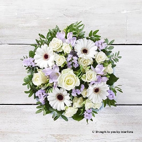 White Germini Ivory rose White Spray Rose Purple Freesia Lilac Statice & Greenery in Blue Glass Vase