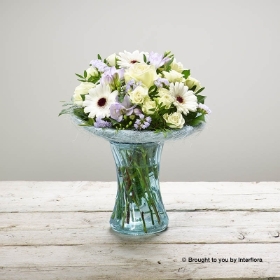 White Germini Ivory rose White Spray Rose Purple Freesia Lilac Statice & Greenery in Blue Glass Vase